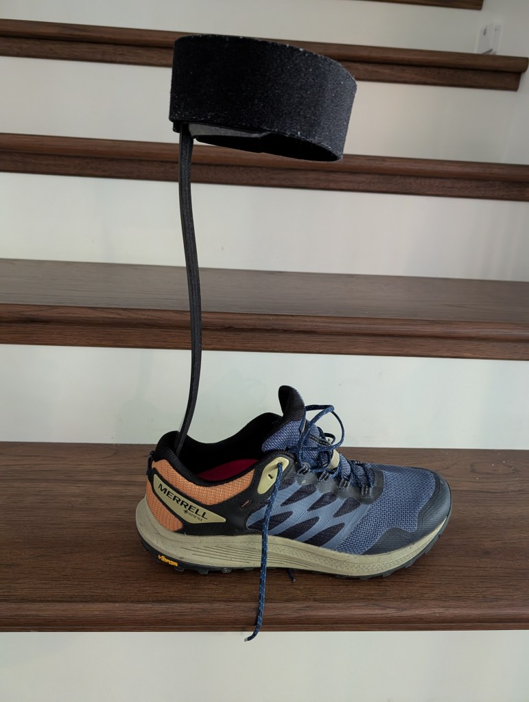 A Merrell running shoe with a black AFO brace..