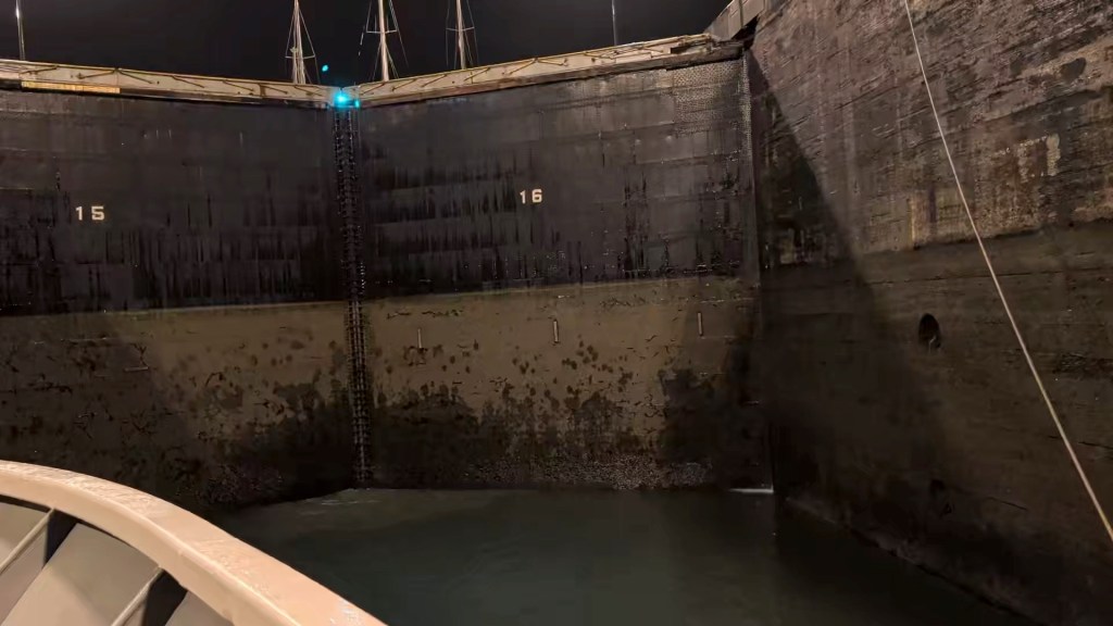 Inside a lock with dark walls marked '15' and '16', water visible below, and mooring lines in view.
