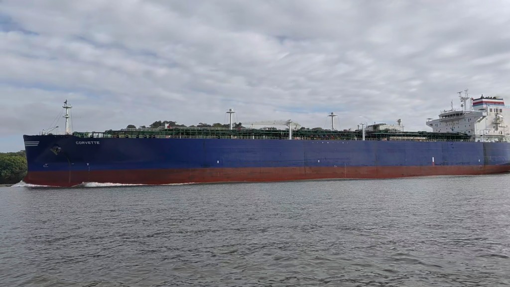 Large cargo ship named Corvette sailing on water under a cloudy sky.