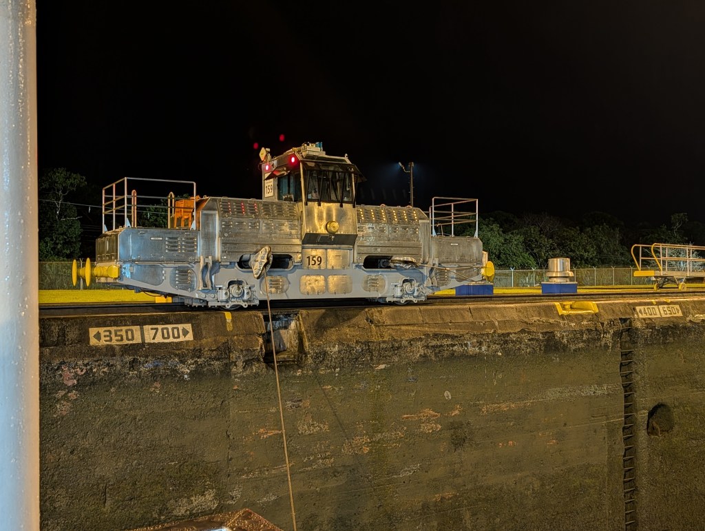 A nighttime view of a large gray locomotive positioned on a lock with various markings and measurements visible on the sides.