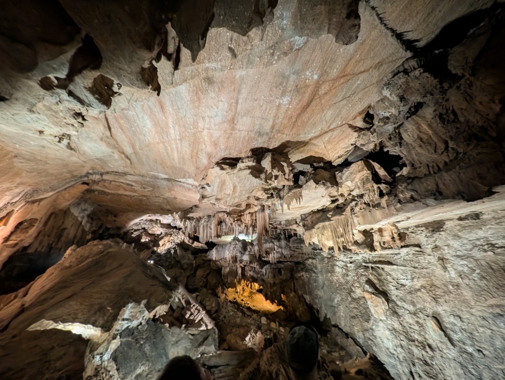 Interior view of a cave with intricate rock formations and stalactites, showcasing a textured ceiling and illuminated sections.
