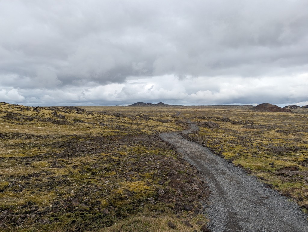 A winding gravel path through a barren, rocky landscape under a cloudy sky.