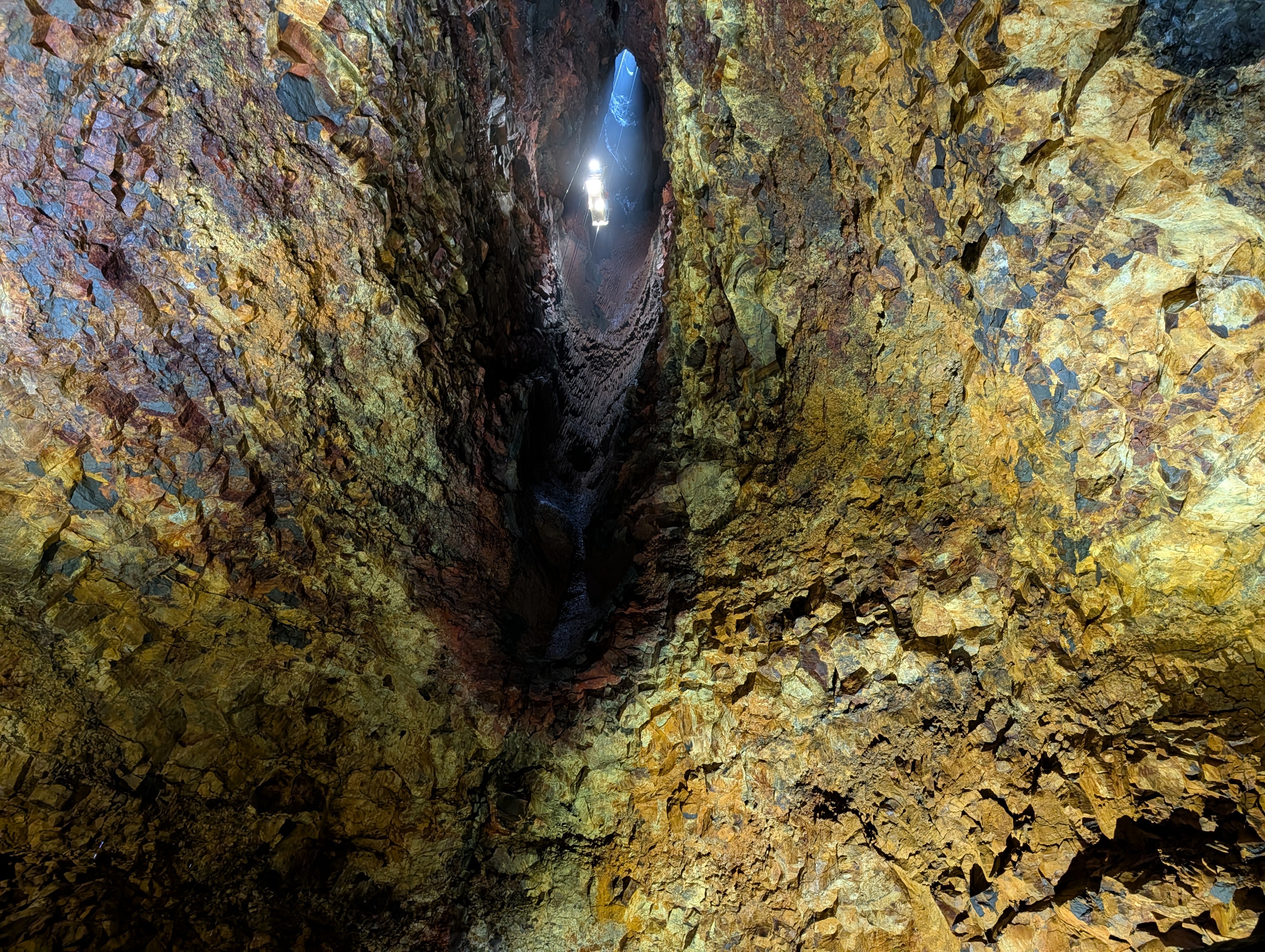 View looking up at a colorful rocky cavern with textures and lighting from above.