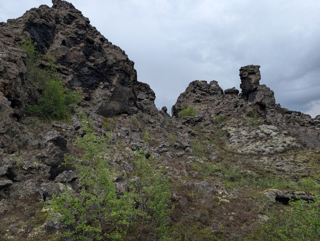 Rocky landscape with rugged terrain and sparse vegetation under a cloudy sky.