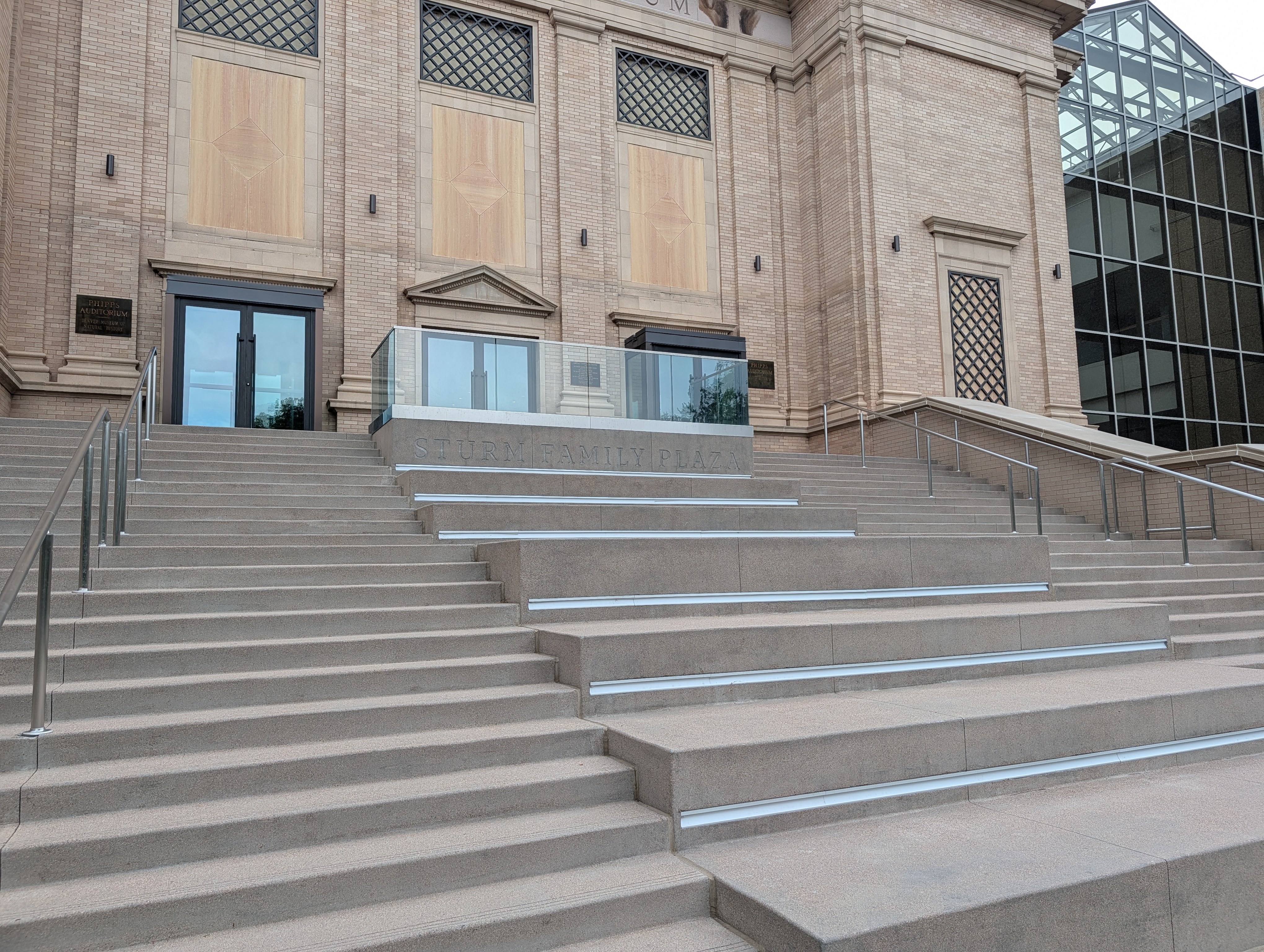 Stairway leading up to the entrance of Sturm Family Plaza, featuring modern handrails and a glass barrier.