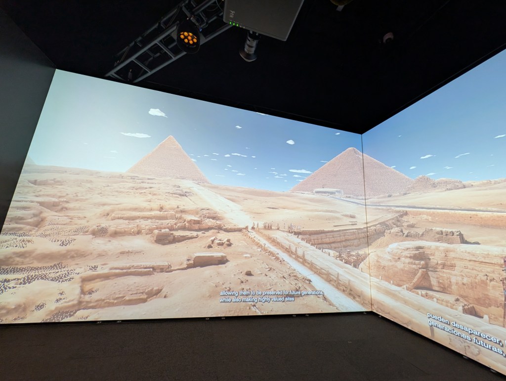 A digital projection of the Pyramids of Giza against a clear blue sky, showcasing the ancient structures in a desert landscape.